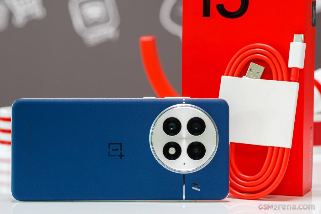 OnePlus 13 smarttelefon i bruk utendørs, viser OLED-skjerm og Hasselblad-kamerasystem bakfra